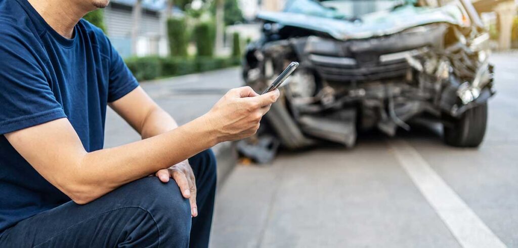man on phone in front of car accident