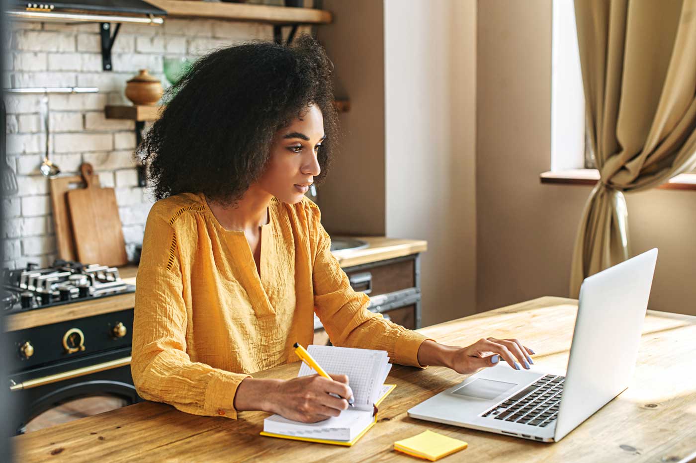 Woman reviewing her laptop and taking notes