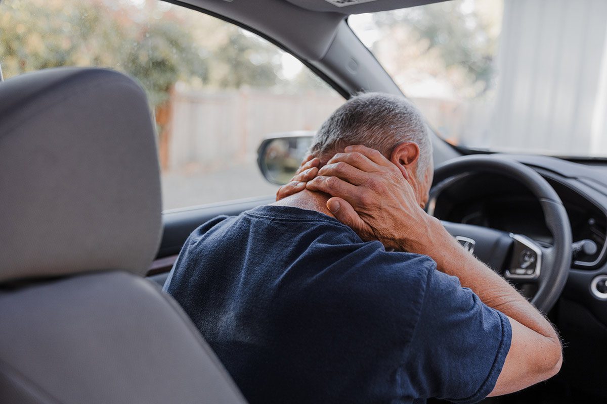 Man in car in pain holding neck