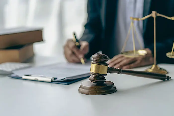 person signing paperwork with a gavel next to him