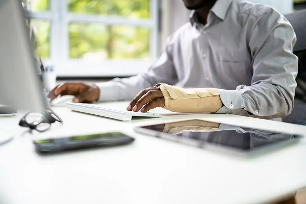 man with brace on hand while working on computer