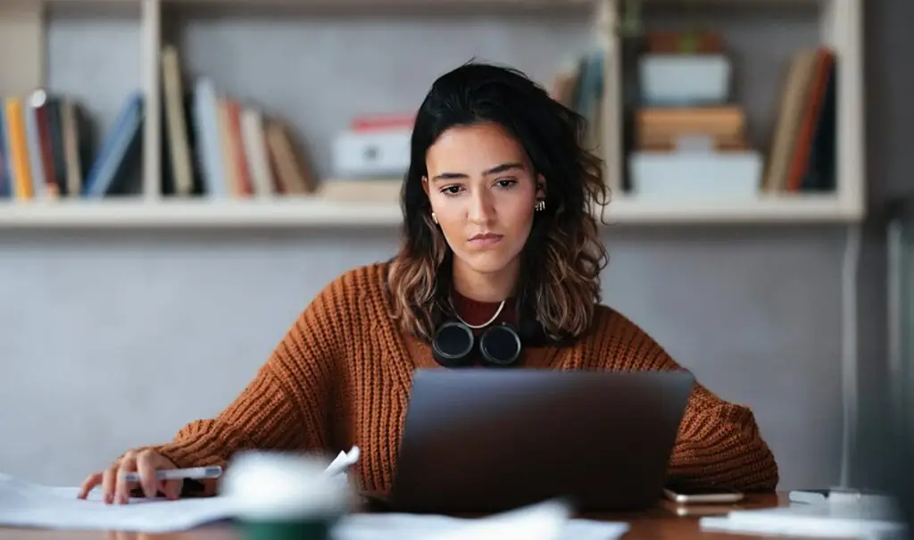 Woman in brown shirt looking at laptop