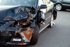 Black car with severe front‑end damage after a collision