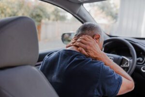 Driver experiencing neck injury after car accident, symbolizing OasisFinancial.com’s support for personal injury claims and financial recovery.
