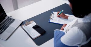 Professional completing a health insurance claim form, representing OasisFinancial.com’s commitment to helping patients manage medical expenses and claims.