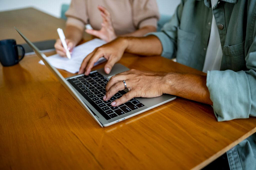 Two people reviewing documents and typing on a laptop during a meeting, representing how personal injury settlements are calculated and evaluated