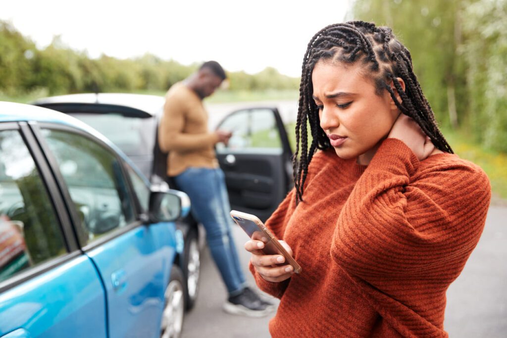 Person holding their neck in pain after a car accident while exchanging information