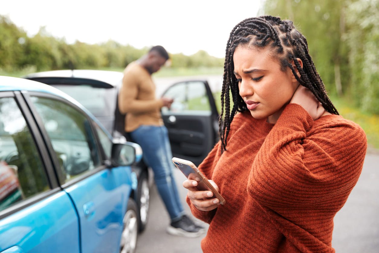 Person holding their neck in pain after a car accident while exchanging information