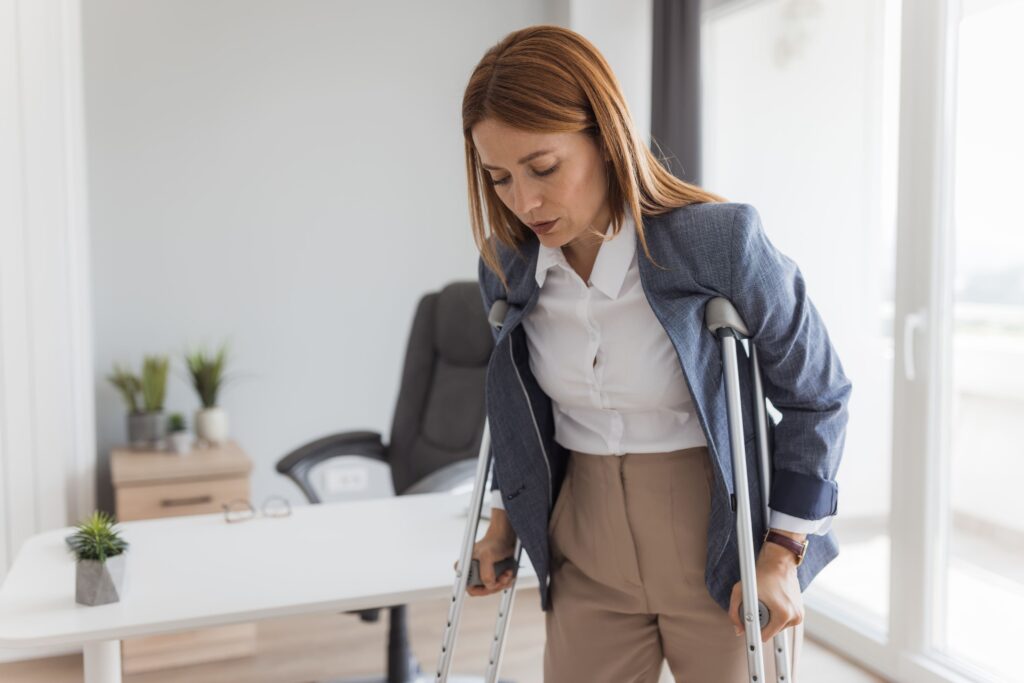 Injured worker on crutches in an office, symbolizing the need for financial support during a workers’ compensation or personal injury claim.